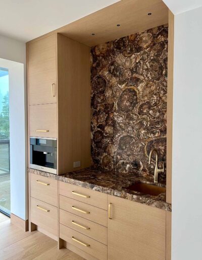 wet bar with brown marble and oak cabinets